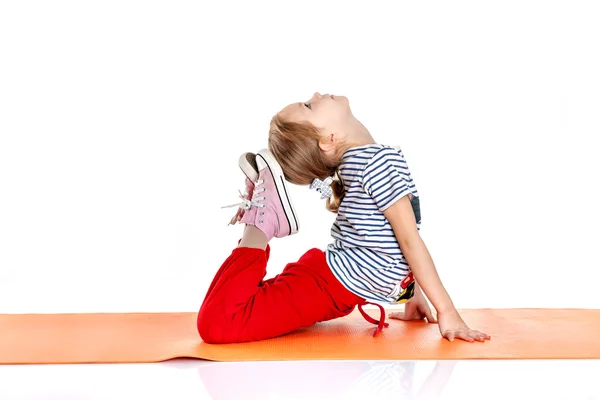 Kleines Mädchen turnt auf einer orangefarbenen Yogamatte. doi — Stockfoto