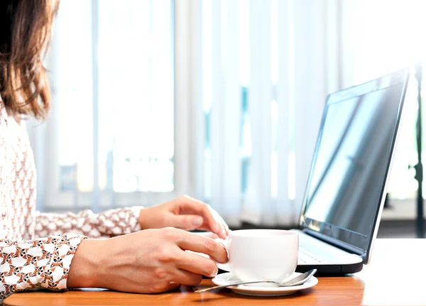 The girl behind the laptop with a cup. Cup in hand.