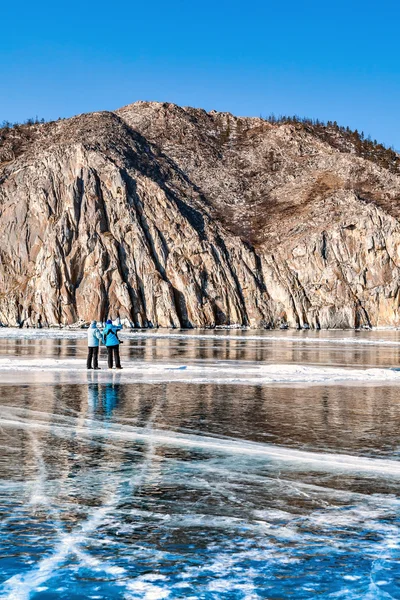 Dos personas en hielo. Fotografía de hielo. reflexión y grietas en el —  Fotos de Stock