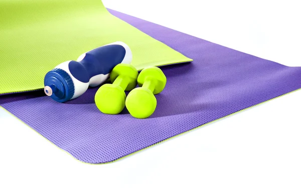 Коврик для йоги. Фиолетовый и зеленый коврик тренировки. Две гантели. бутылка о — стоковое фото