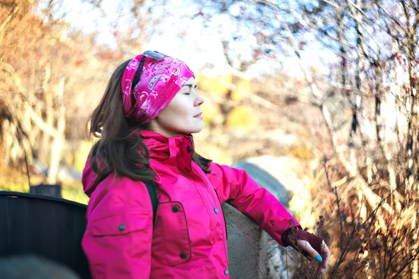 Girl in the autumn forest. Close eyes. Bright jacket.