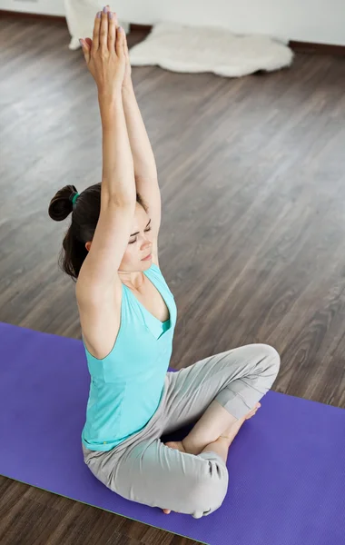 La chica en la posición de loto. Estera de yoga púrpura. Yoga en casa . — Foto de Stock