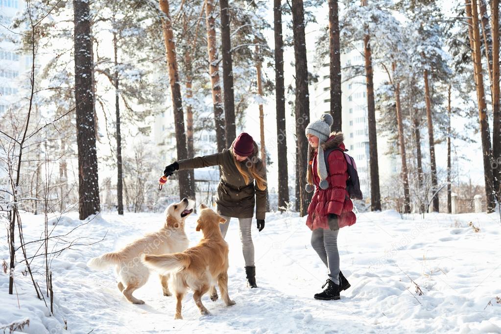 Two young girls playing with a dog in the snow
