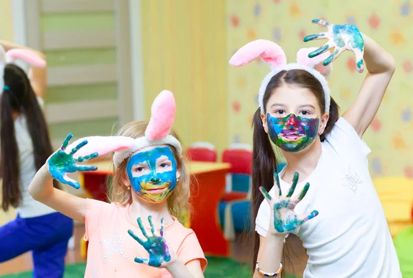 Two little funny girls paint colored paint on his face — Stock Photo, Image