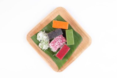 Karışık renkli kuih nyonya tatlı çöl üzerinde palmiye yaprağı tabağı beyaz arka planda