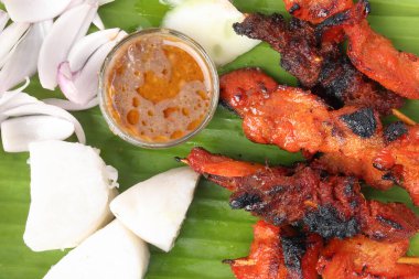 Tavuklu koyun eti, Satay 'la tanış. Nasi' yi hazırla. Yapışkan pirinç keki dilimlenmiş soğan salatalığı tatlı fıstık sosu muz yaprağı bambu sepeti üzerinde.