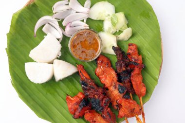 Tavuklu koyun eti, Satay 'la tanış. Nasi' yi hazırla. Yapışkan pirinç keki dilimlenmiş soğan salatalığı tatlı fıstık sosu muz yaprağı bambu sepeti üzerinde.