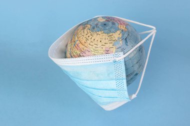 Dünya haritası. Mavi arka planda yüz maskesi takıyor.