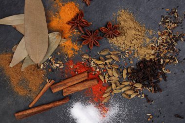 Karışık baharatlı tarçınlı kakule karanfil defne yaprağı ahşap biber kimyonlu zerdeçal destekli tuz siyah sayfada.