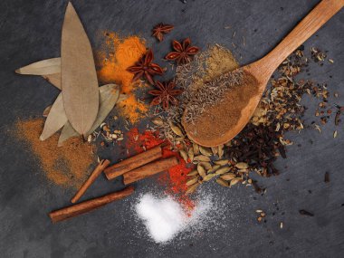Karışık baharatlı tarçın kakule karanfil defne yaprağı ahşap biber kimyon zerdeçal güçlendirilmiş siyah tahta tahta kaşık
