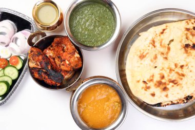 Baharatlı kırmızı tavuk ızgara tikka tandır nan ekmeği yeşil ıspanak körili yoğurt sosu dal salatalık soğan salatası metal paslanmaz çelik pirinç pirinç bakır kap beyaz arka planda