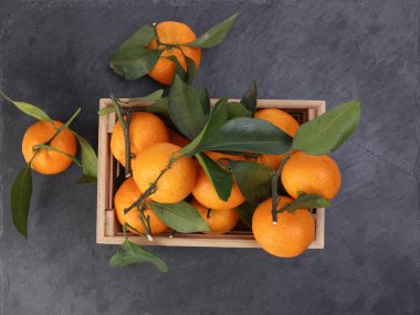 Ahşap sandıkta turuncu turuncu yaprak siyah mermer arka planda üst görünüm