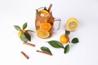 Yeşil yapraklı tarçınlı limonlu portakal çayı şeffaf cam kavanozda çubuk beyaz arka planda bütün meyve.