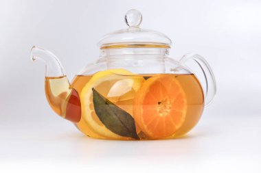 Likit çay, portakal dilimi yeşil yaprak tarçın şeffaf cam çaydanlık, beyaz arka plan.