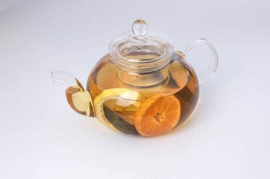 Likit çay, portakal dilimi yeşil yaprak tarçın şeffaf cam çaydanlık, beyaz arka plan.