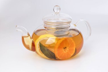 Likit çay, portakal dilimi yeşil yaprak tarçın şeffaf cam çaydanlık, beyaz arka plan.