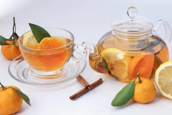 Likit çay portakal dilimi yeşil yaprak tarçın şeffaf cam çay fincanı çay fincanı demliği beyaz arka planda.