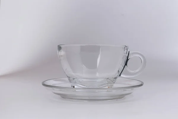 空の透明なガラスを通して参照してくださいコーヒーティーカップソーサー白い背景に — ストック写真