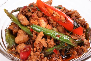 Merdivenler kızarmış Tayland fesleğeni kıyılmış baharatlı kırmızı kırmızı biber, cam kasede beyaz arka planda servis ediliyor.