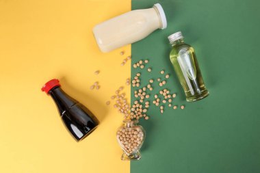 Soya fasulyesi sosu şişesinin etrafına, sarı yeşil arka planda Hart şeklindeki cam şişeden fışkıran soya fasulyesi yağları.