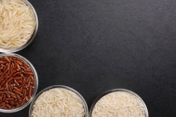 Long grain basmati medium grain jasmine short grain pilaf polau risotto brown low glycaemic index gi rice in small glass bowl on black background copy text space top flat lay view border frame