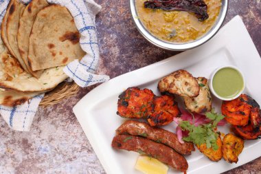 Karışık ızgara kebap tavuk sığır eti karides naneli balık limon salamura soğan sepeti chapati naan tandoori dal mercimek kızartma tadka bakır kap rustik arka plan üzerinde