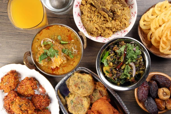 Bengali iftar Ramazan kahvaltısı olgunlaşmış baharatlı piaju soğan doğrayıcısı patlıcan tanpura patates pirzolası haleem jilapi khichuri pirinç chana sola körisi kırsal ahşap masa üzerinde.