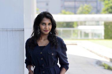 Koyu mavi tulumlu, çekici, güzel Hintli kadın şehir duvarına yaslanıp kameraya bak.