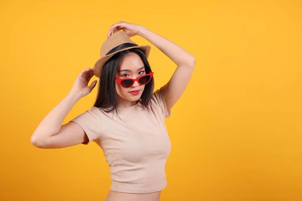 Beautiful young south east Asian woman red frame sunglass hat pose style fashion peak happy on yellow orange background