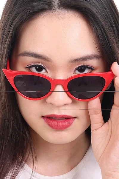 Beautiful young south east Asian woman peaking over wearing red frame dark sunglass pose fashion style white background