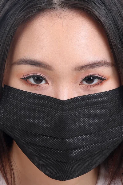 Beautiful young south east Asian woman wearing black three ply anti virus surgical face mask on white background