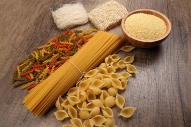 Kuru çiğ spagetti conchiglie deniz kabukları fusilli mantar renginde makarna kuskus pilavlı erişte ahşap arka planda beehoon verity.