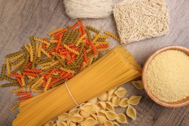 Kuru çiğ spagetti conchiglie deniz kabukları fusilli mantar renginde makarna kuskus pilavlı erişte ahşap arka planda beehoon verity.