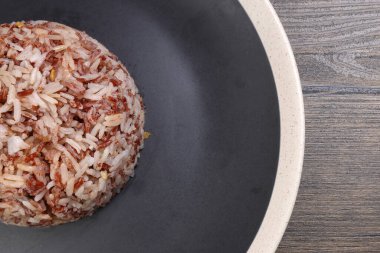 Nasi dagang özel kahverengi pirinç hindistan cevizi sütü ve baharatla pişirilmiş siyah kaplama siyah ahşap arka planda