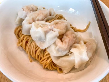 Beyaz kâse çubuklarıyla doğranmış zencefilli soya soslu karidesli kuru erişteli Çin mantısı.