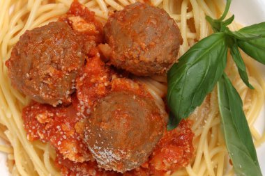 Pişmiş spagetti soslu köfte peynir tozu. Tahta tabakta fesleğen.