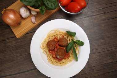 Pişmiş spagetti soslu köfte köftesi peynir tozu. İçinde Roma domates kasesi, cam kase, soğan, sarımsak, ahşap masa duvarı tarifi.