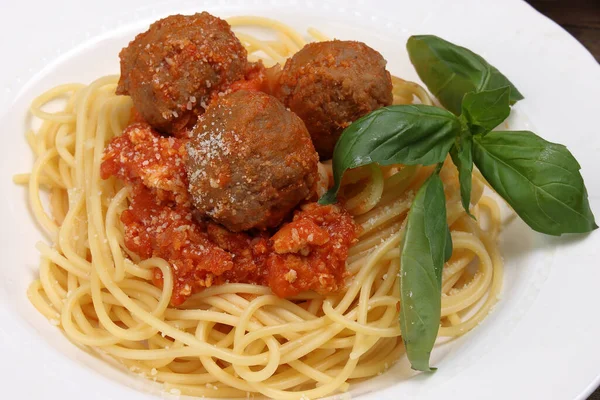 Cooked spaghetti tomato meatball sauce cheese powder basil on white plate wooden table