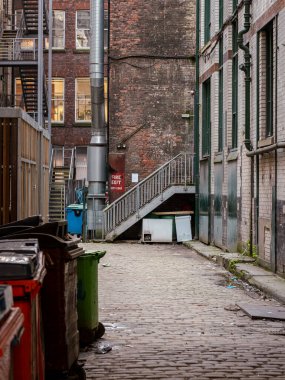 Manchester, İngiltere, Mart 04, 2024 kaldırımlı sakin şehir arka sokağı, endüstriyel yangın çıkışı ve yıpranmış tuğla duvarlar. Kumlu şehir atmosferi eski bir sanayi bölgesindeki günlük yaşamı yansıtıyor