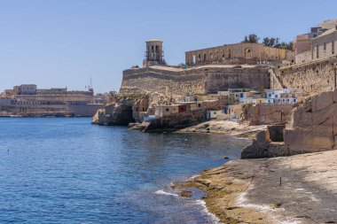 Valletta, Malta - 8 Nisan 2024: Valletta 'nın şehir duvarlarının altındaki tarihi kireçtaşı tahkimatı ve kayalık kıyı şeridine bakın.