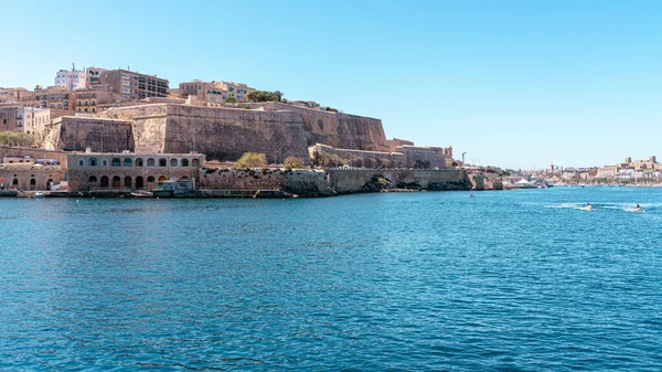 Valletta, Malta - 8 Nisan 2024: Valletta 'nın tarihi kireçtaşı tahkimatı ve liman limanını Sliema' dan gelen feribot rotasından, turkuaz Akdeniz suyu ve temiz bir gökyüzü altında küçük teknelerle geniş açıdan görmek