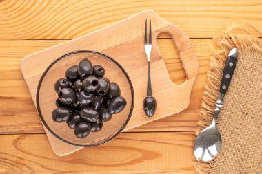 Konserve siyah zeytinler ahşap bir masada, üst manzara.