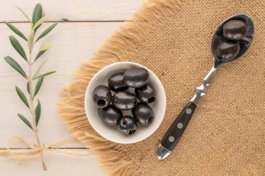 Konserve siyah zeytinler ahşap bir masada, üst manzara.