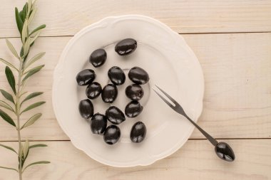 Konserve siyah zeytinler ahşap bir masada, üst manzara.