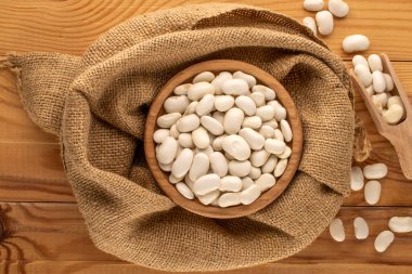 Ahşap bir masada pişmemiş beyaz fasulye, yakın plan, üst manzara..