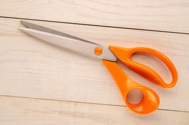 Sewing scissors on a wooden table, top view, close-up.