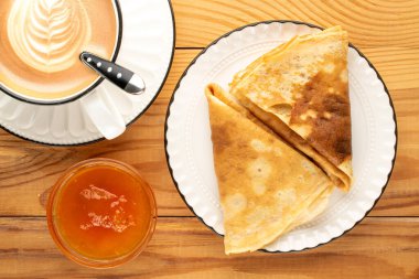 Tahta bir masada kayısı reçelli krep, makro, üst manzara..