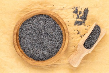 Kraft kağıdında mutfak gereçleri olan kuru haşhaş tohumları, yakın plan, üst manzara..