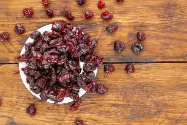 Seramik bir tabakta kurumuş kirazlar ahşap bir masanın üstünde, yakın plan, üst manzara.