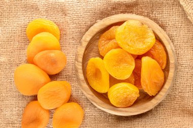 Kurutulmuş kayısılar, jüt kumaşında ahşap bir çay tabağı, yakın plan, üst manzara..